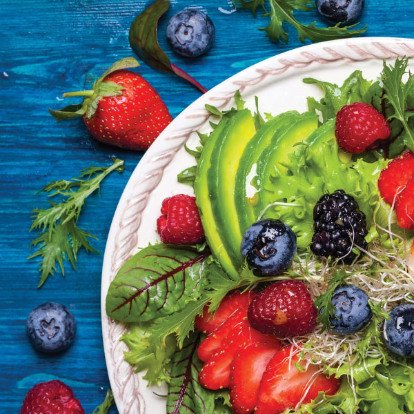 A salad with berries and avocado on a plate.