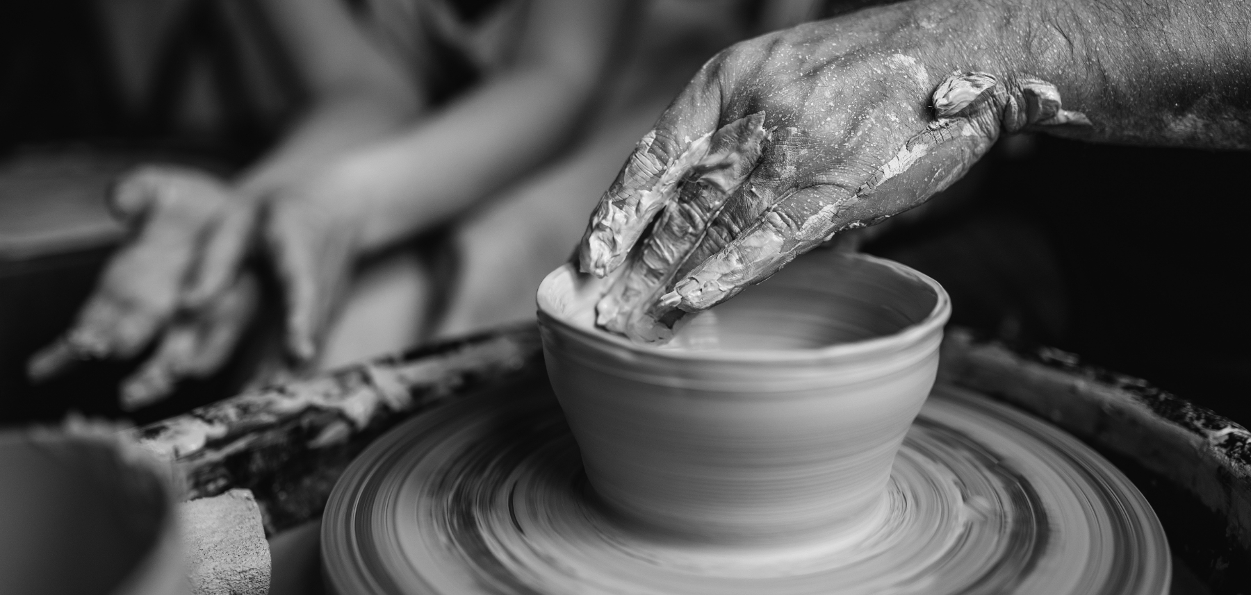 A black and white photo of a person working on a potter's wheel.