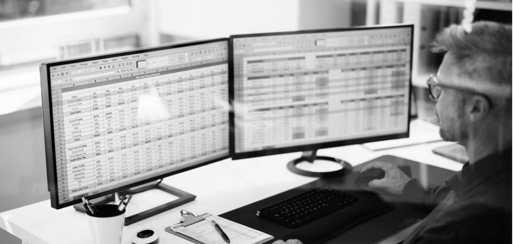 A man sitting at a desk with two monitors.