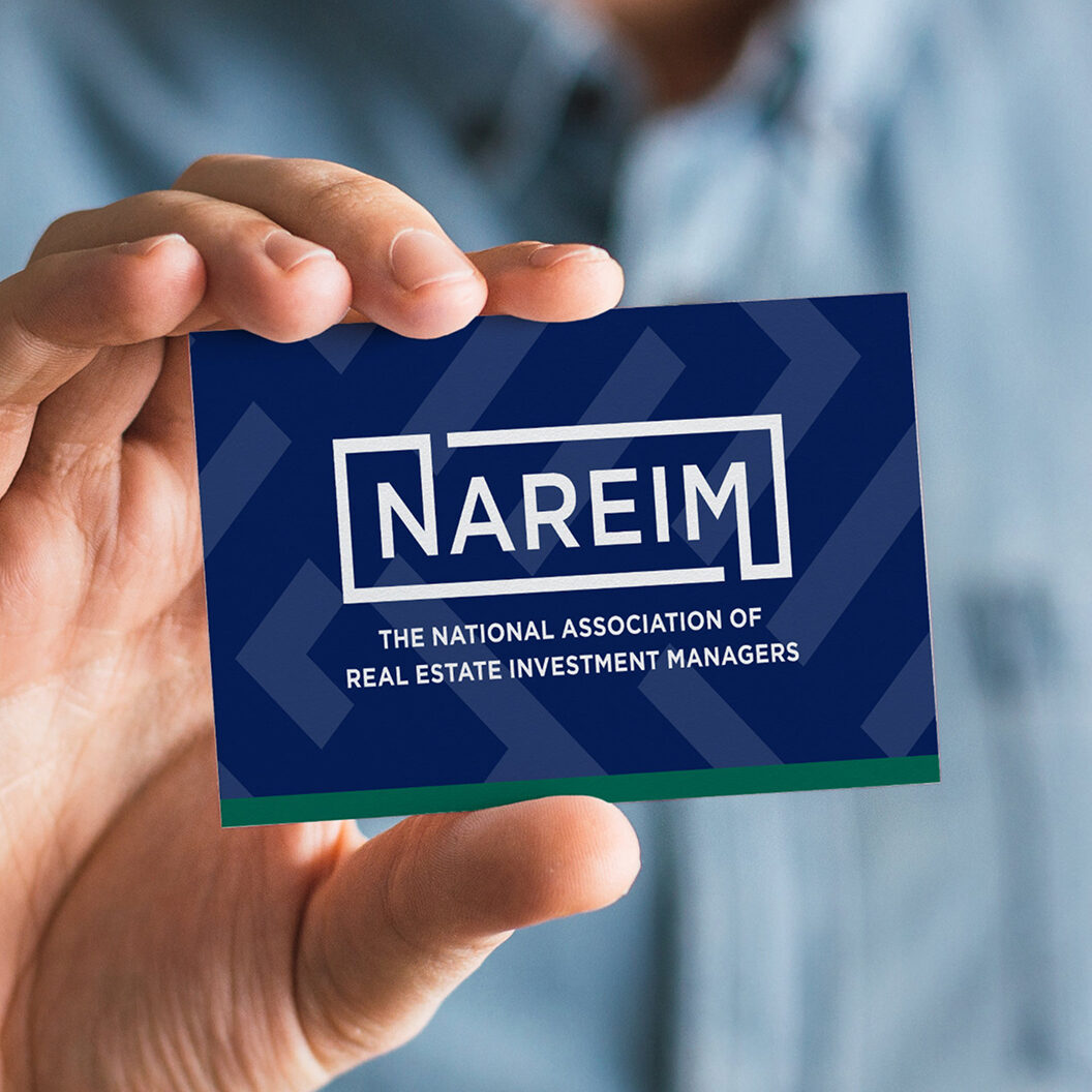 NAREIM business card being held up by a business man
